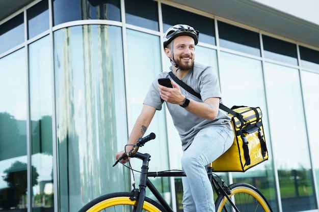 Courrier de livraison express avec sac isotherme tenant le téléphone à vélo