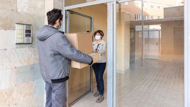 Le courrier de livraison livre le colis à la femme à sa porte