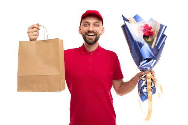 Courrier de livraison en uniforme rouge tenant un sac en papier kraft et un bouquet de fleurs