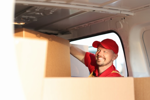 Photo courrier masculin mettant des boîtes en carton dans la voiture