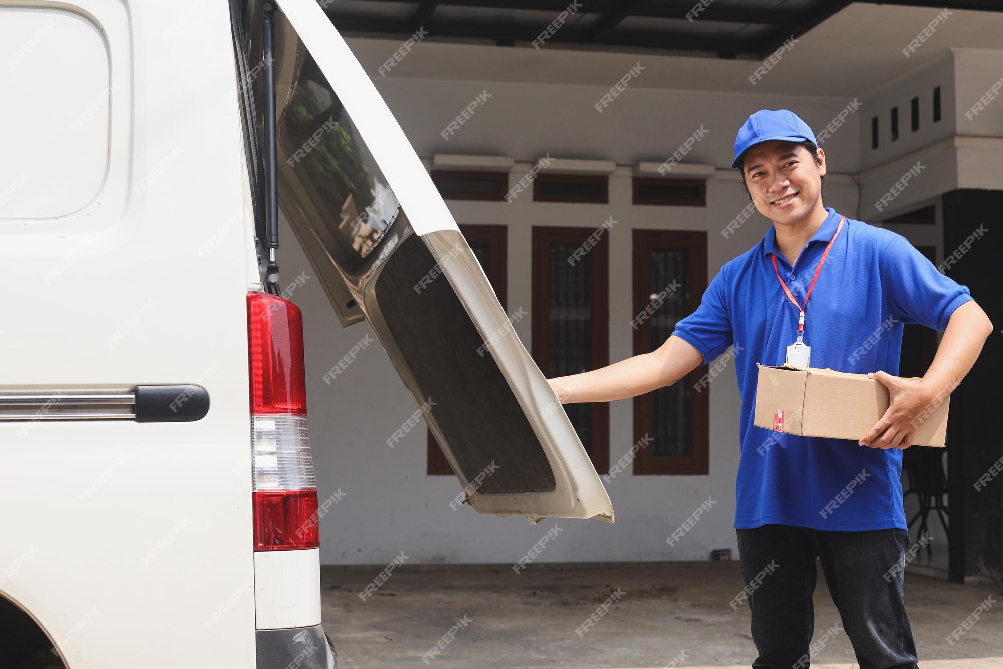 Courrier Regardant La Caméra En Souriant Tout En Ouvrant Le Capot Du Coffre  Arrière De La Voiture Pour Charger Les Colis