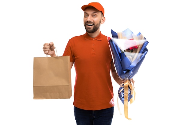 Courrier de service de livraison avec des sacs en carton artisanaux et un bouquet de fleurs en regardant la caméra