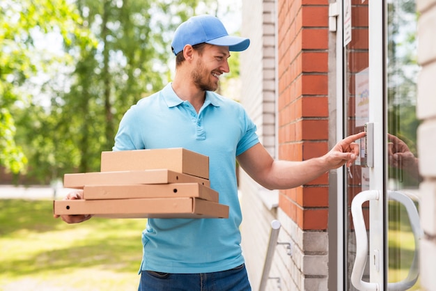 Courrier souriant lors de la livraison de pizzas près de l'entrée d'un immeuble