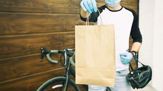 Le courrier sur le vélo livre le sac en papier avec l'ordre à la personne