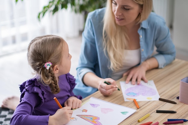 Un cours d'art préscolaire pour professeur de créativité aide une petite fille à apprendre le dessin et la peinture