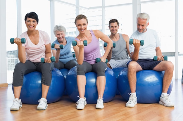 Cours de conditionnement physique avec des haltères assis sur des balles d&#39;exercice