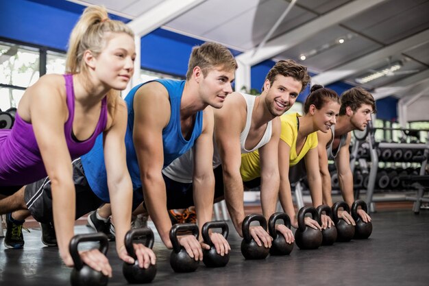Cours de conditionnement physique en position de planche avec des haltères dans la salle de gym