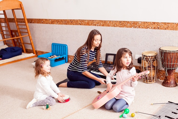 Cours de création musicale. La jeune enseignante joue avec les enfants, petit orchestre