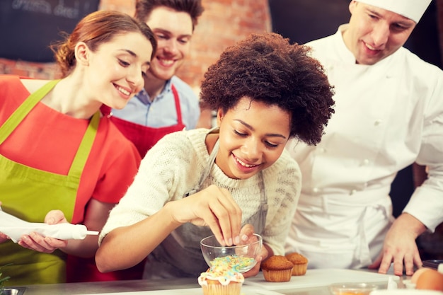 Photo cours de cuisine, cuisine, boulangerie, concept de nourriture et de personnes - groupe heureux d'amis et chef cuisinier cuisinant dans la cuisine
