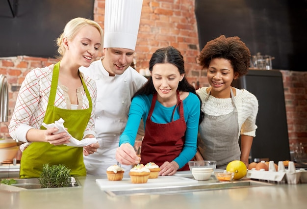 cours de cuisine, cuisine, boulangerie, concept de nourriture et de personnes - groupe heureux de femmes et de chefs cuisiniers cuisinant dans la cuisine