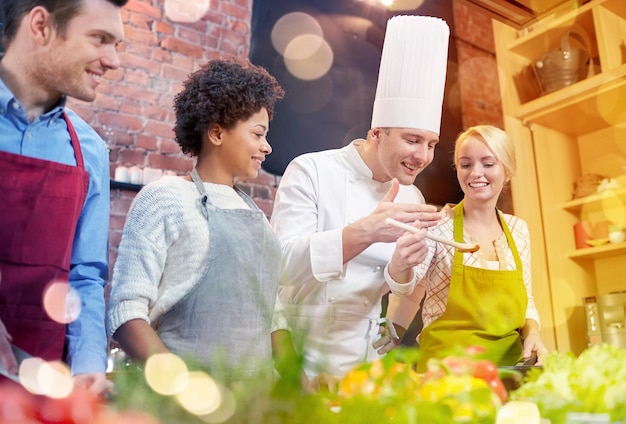 Photo cours de cuisine nourriture culinaire et concept de personnes groupe heureux d'amis et chef cuisinier masculin cuisiner dans la cuisine