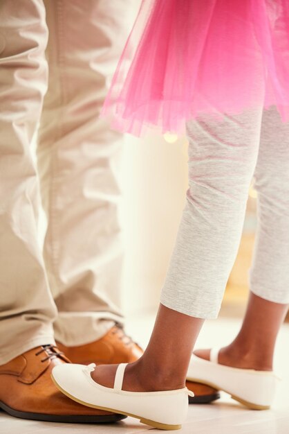 Cours de danse avec papa Photo d'une fille méconnaissable dansant sur les pieds de son père à la maison