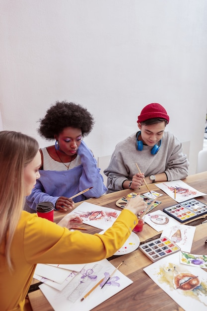 Cours de dessin. Trois étudiants en art talentueux à la mode qui fréquentent un cours de dessin ensemble