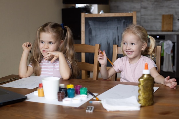 Cours de dessin virtuel de deux filles à la maison des enfants regardant un ordinateur portable de leçon