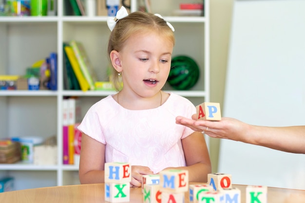 Cours de développement et d'orthophonie avec une fille. Exercices d'orthophonie et jeux avec des lettres.