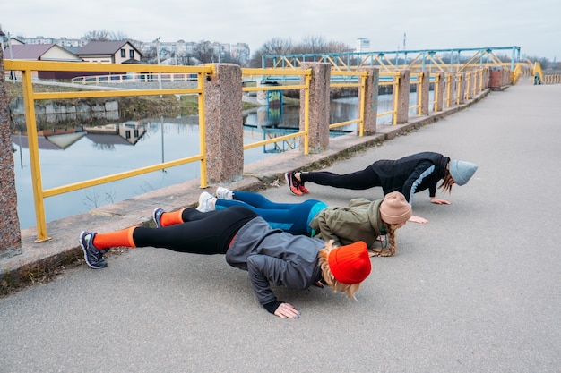 Cours de fitness en groupe à l'extérieur. Cours de gym organisés mis en place dans les parcs publics. Trois femmes s'entraînant ensemble dans le parc public. Concept de santé, de bien-être et de communauté.