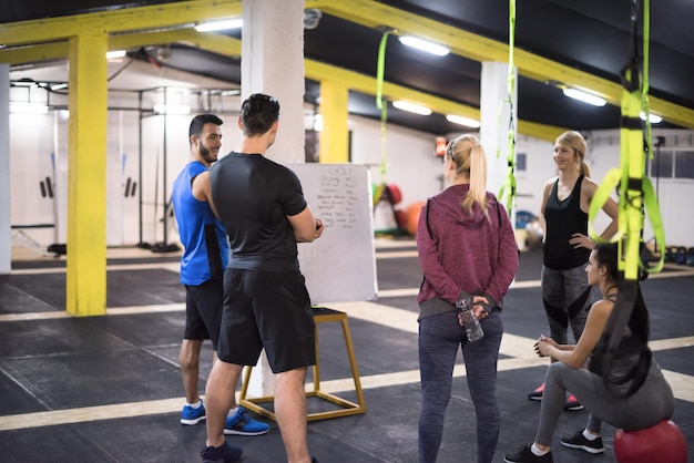Cours de formation.groupe de jeunes athlètes recevant des instructions de l'entraîneur avant l'exercice à la salle de fitness cross