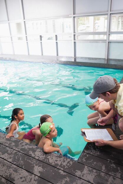 Cours de natation mignon à l&#39;écoute de l&#39;entraîneur