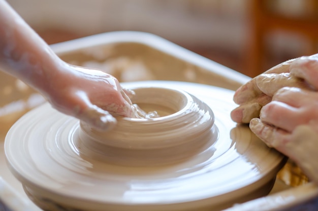 Cours de poterie passe-temps faits à la main cours de maître à l'atelier potier formant de l'argile sur la roue tournante avec un petit enfant étudiant