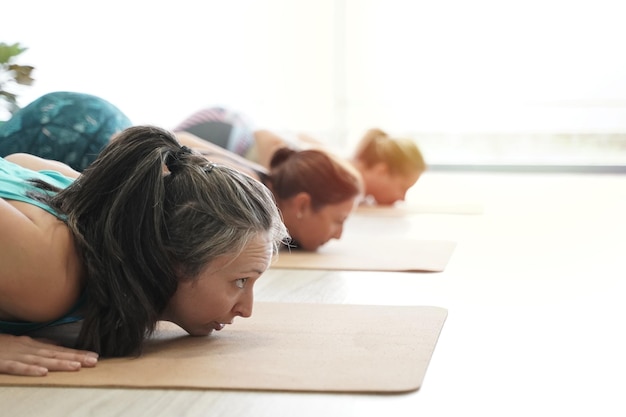 Cours de yoga Gros plan d'un groupe de femmes pratiquant le yoga à l'intérieur faisant la posture Ashtanga namaskara faisant partie de la séquence classique surya namaskar