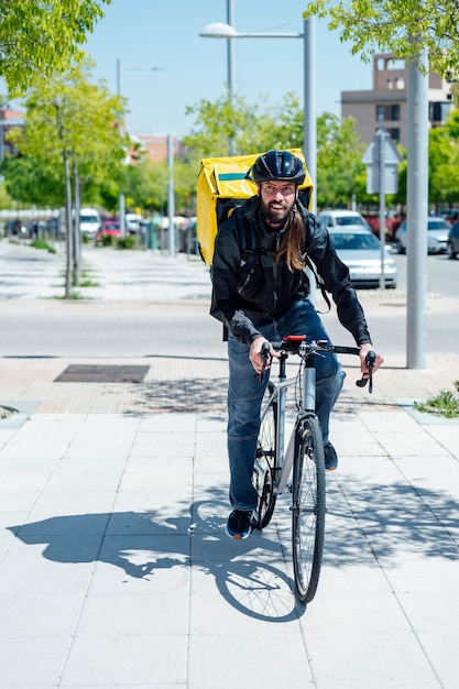 coursier livrant de la nourriture avec un sac à dos thermique jaune, faisant du vélo en ville. Concept de service de livraison de nourriture