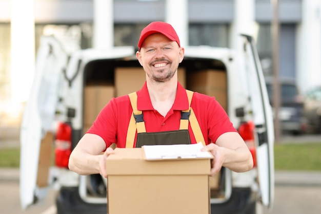 Photo un coursier souriant se tient devant une camionnette avec un colis