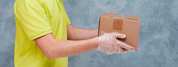 Le coursier tient des boîtes en carton dans des gants jetables. Livraison sans contact pendant la période de quarantaine du coronavirus