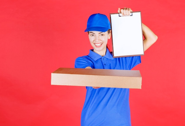 Coursière en uniforme bleu tenant une boîte à pizza à emporter en carton et présentant la liste des signatures .