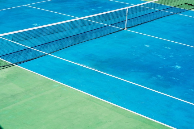 Court de tennis désert avec greentrees en arrière-plan dans un parc public un matin d'été ensoleillé