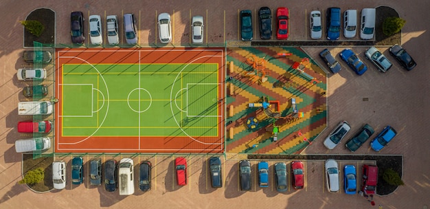 Un court de tennis est clôturé et un parking au centre du complexe résidentiel moderne.