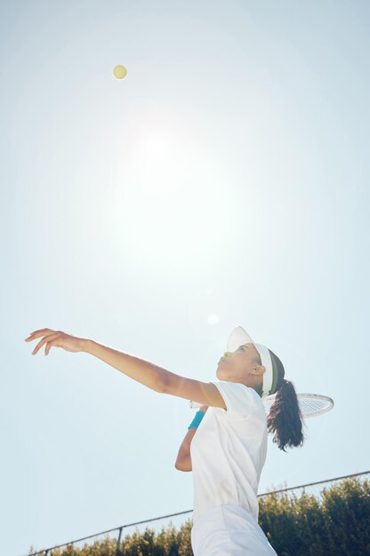 Court de tennis en plein air fille et balle dans le ciel après un coup professionnel avec une raquette de sport en match Femme championne de compétition et athlète talentueuse et en forme avec une technique de jeu experte