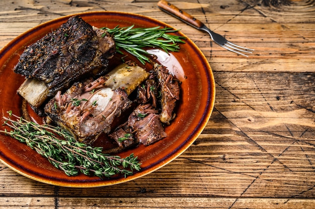 Courtes côtes de bœuf grillées au thym sur une assiette rustique. fond en bois. Vue de dessus. Espace de copie.