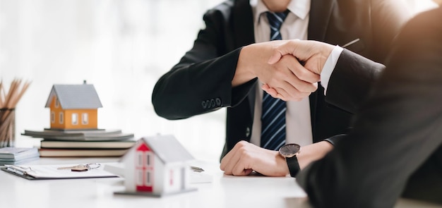 Courtier immobilier et client se serrant la main après la signature d'un contrat de prêt immobilier et concept d'assurance