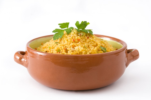 Couscous aux légumes dans un bol brun isolé sur blanc