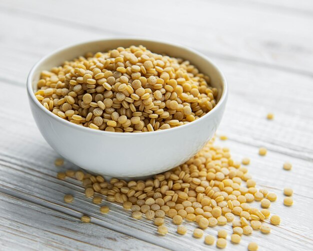 Couscous cru dans un bol blanc et une cuillère sur la table