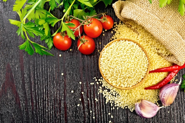 Couscous cru dans un bol et un sac de toile de jute, ail, tomates