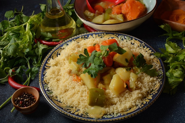 Couscous cuit au persil vert dans une assiette en céramique et ragoût de légumes.