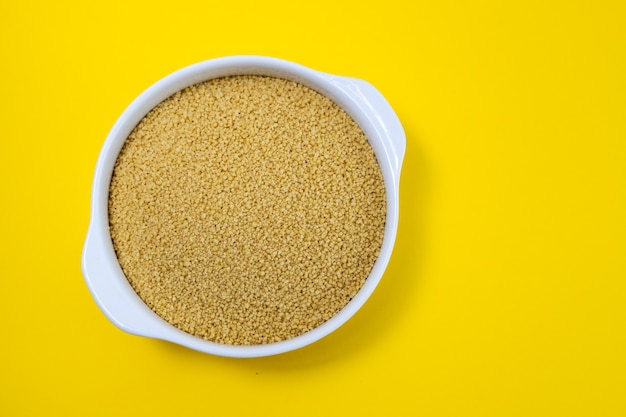 Couscous dans un bol blanc sur fond de papier jaune