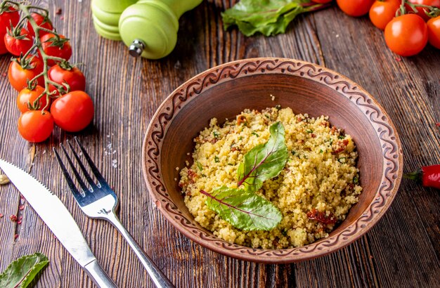 Couscous dans un bol avec de l'huile d'olive et des tomates séchées sur fond de bois cuisine orientale photo horizontale