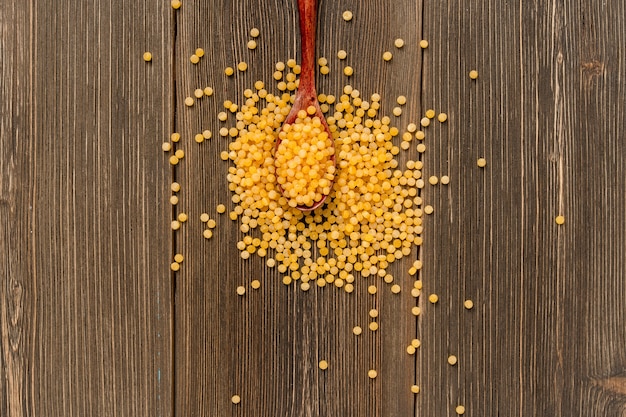 Le couscous sec est dispersé sur une table en bois