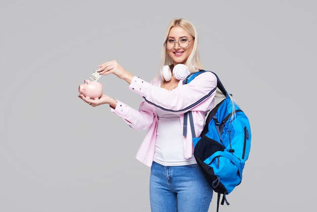 Coût des études collégiales. Portrait a souligné la femme avec sa tirelire dans les mains. Étudiant ayant du mal à payer pour le concept de frais de scolarité universitaire. Expressions du visage. Espace gris neutre