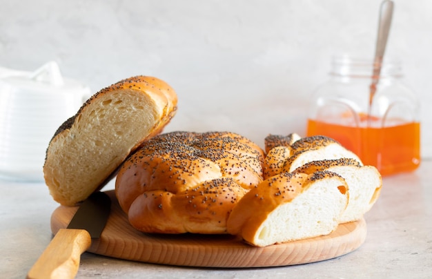 Un couteau challahs et demi et des tranches sur un pot de confiture et une théière en bois