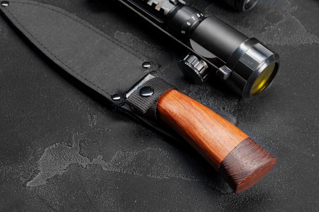 Couteau de chasse et viseur optique pour carabine sur fond gris