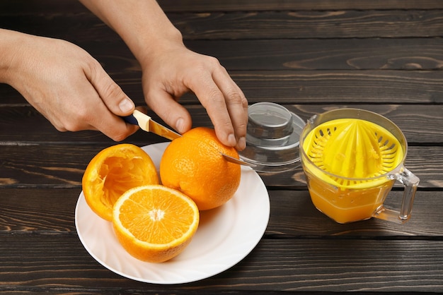 Couteau coupé à la main, faire des moitiés d'oranges pour ensuite presser le jus frais sur le presse-agrumes à la maison