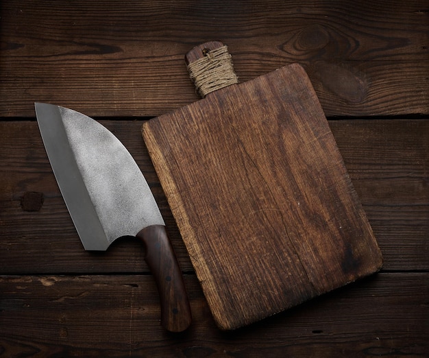 Couteau de cuisine en métal et planche à découper en bois vide sur une table en planches de bois marron, vue de dessus