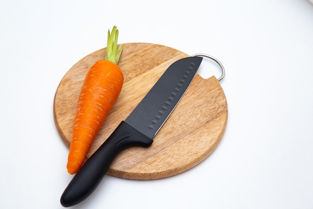 Couteau de cuisine noir de luxe et carotte sur planche à découper isolé sur blanc