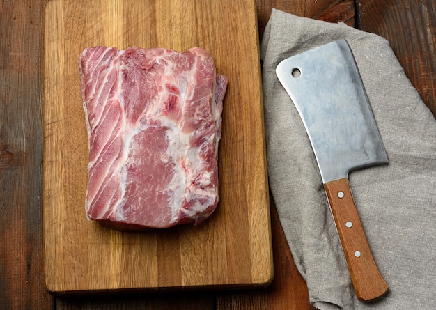 Couteau et filet de porc cru sur une planche à découper en bois