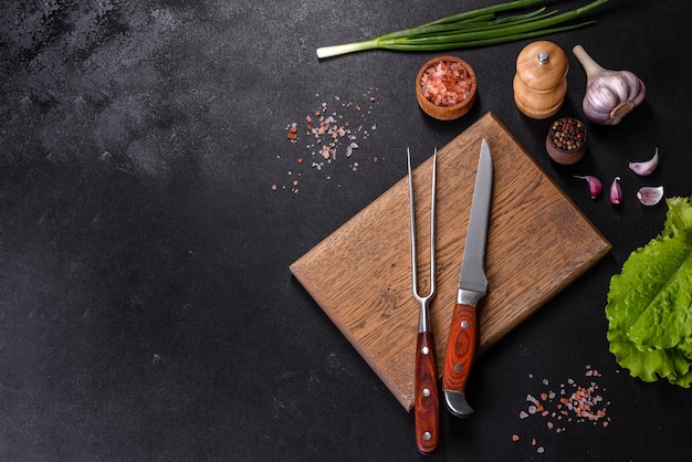 Couteau fourchette épices et herbes planche à découper sur un fond de béton foncé