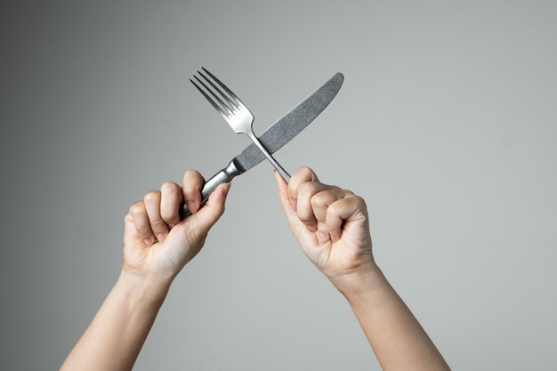 Couteau et une fourchette avec la main sur la cuisine ustensile fond gris pour la cuisine