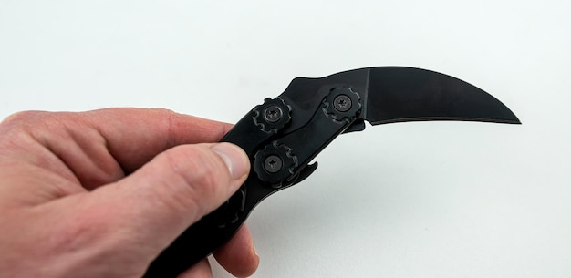 Couteau karambit noir à la main sur fond blanc isolé